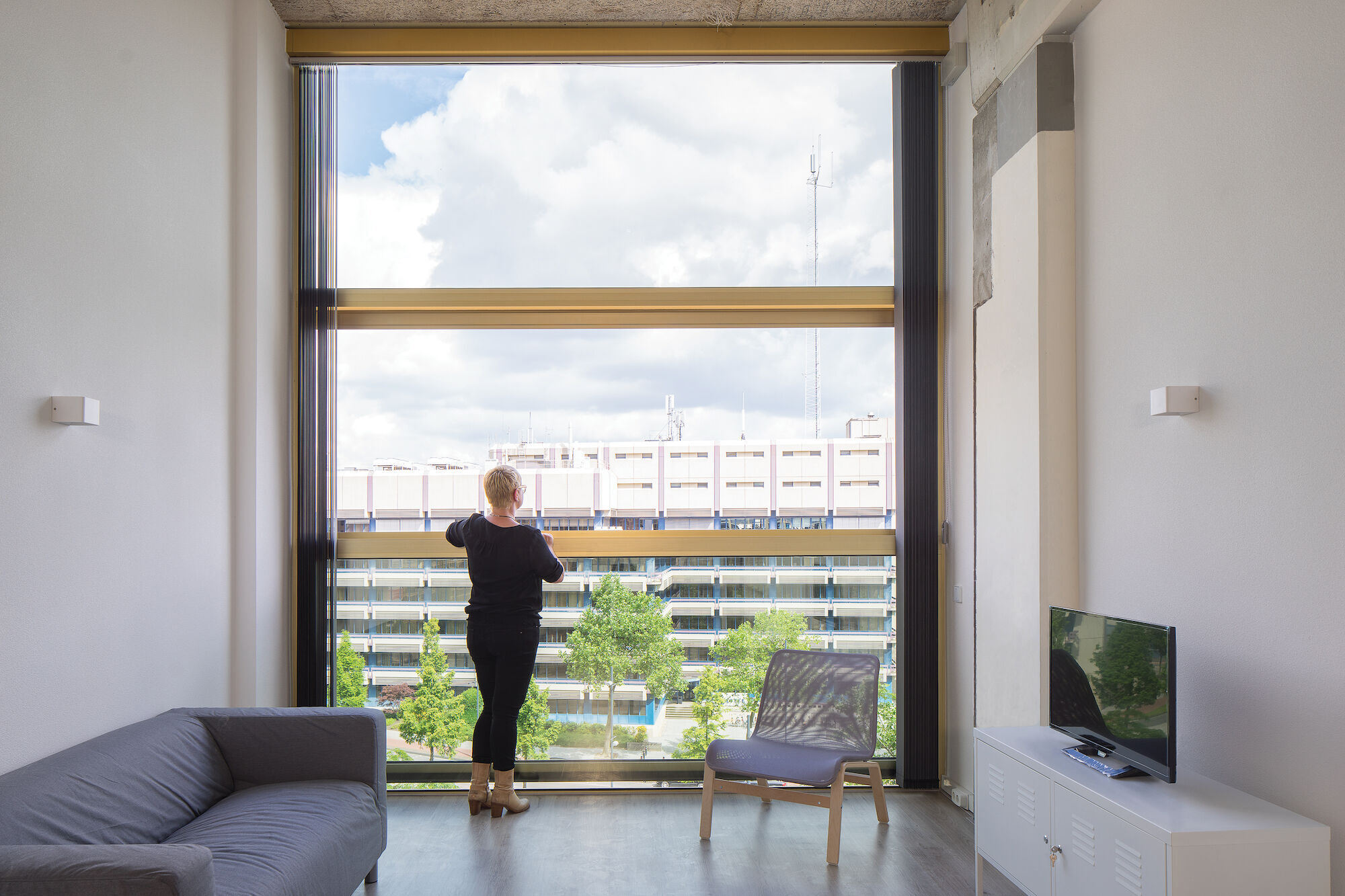 Een vrouw kijkt uit een groot Reynaers Aluminium raam in het Philips Lighting gebouw.