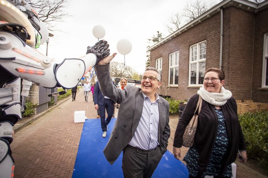 Gasten voor het jubileum komen aan op een blauwe loper.