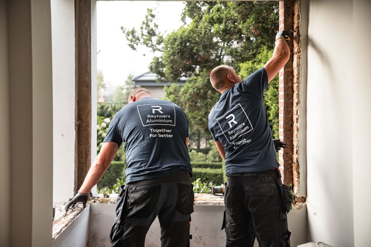 Twee Reynaers Aluminium installateurs ontmantelen oude ramen op locatie.
