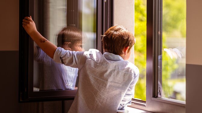 Child looking out of an open window.