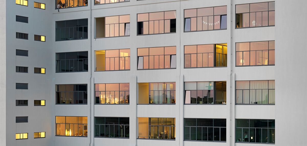 Verlichte ramen in een strak appartementsgebouw.