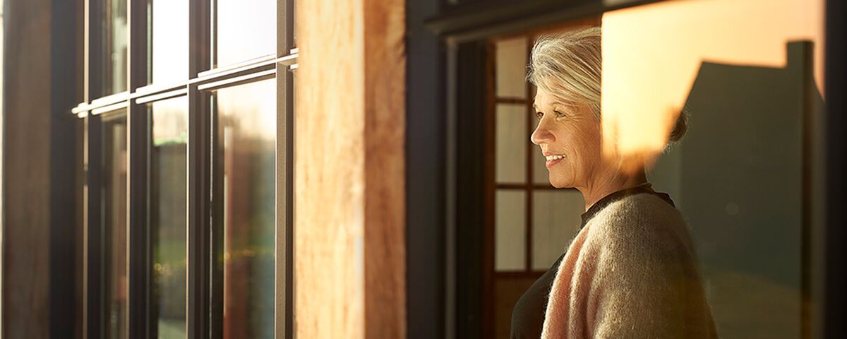 Woman looking at sunset from behind Reynaers Aluminium windows.