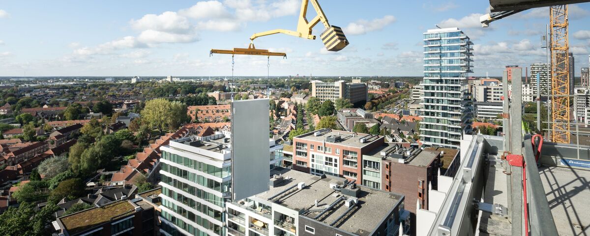 Modulair gebouw paneel opgetild naast wolkenkrabber.