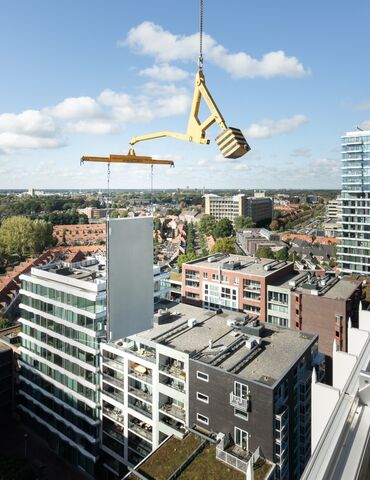 Modulair gebouw paneel opgetild naast wolkenkrabber.